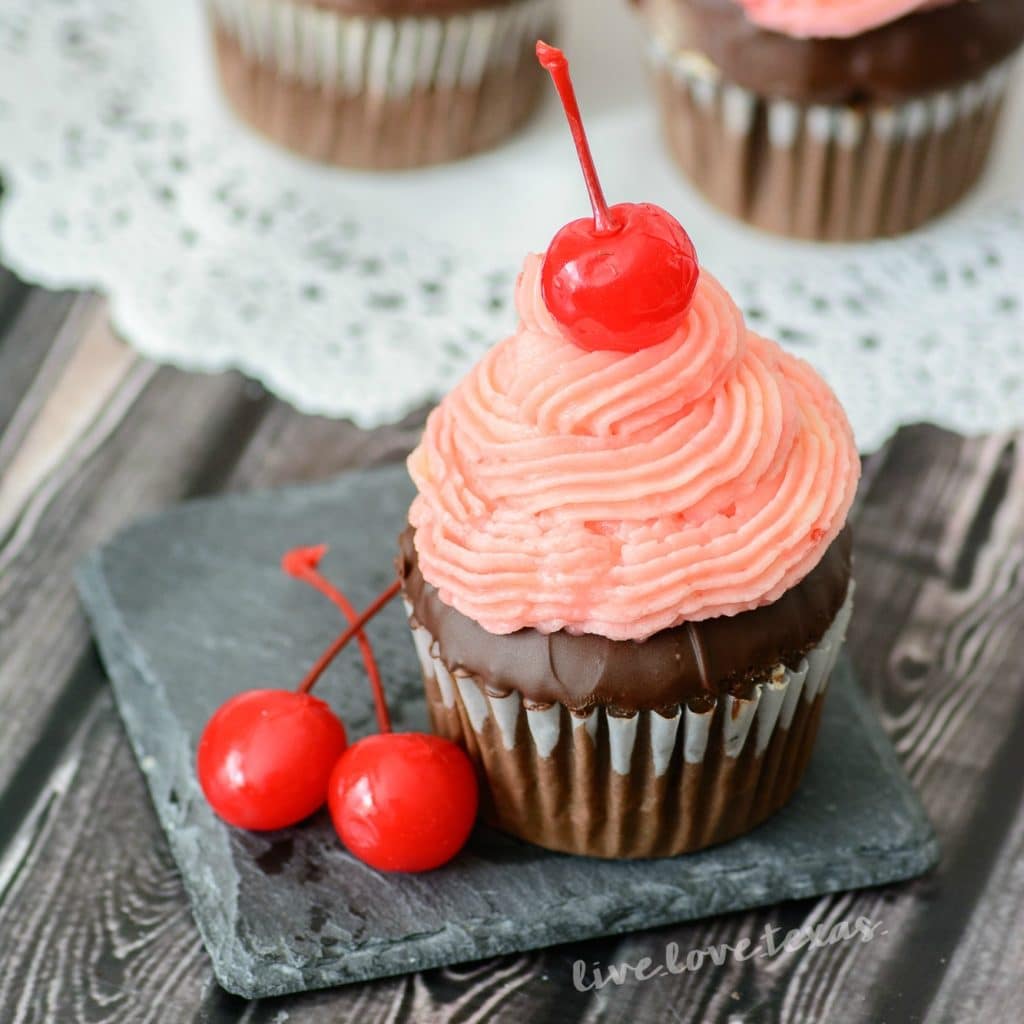 Chocolate cupcakes topped with cherry frosting.