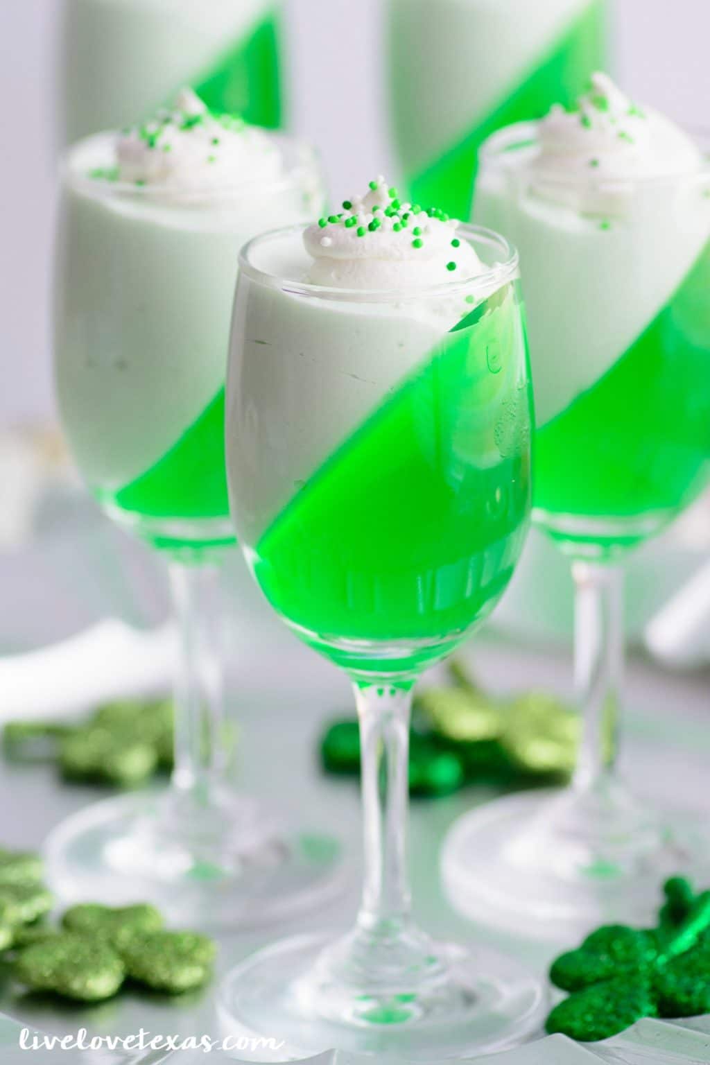 Finished St. Patrick's Day Jello Cool Whip Parfait dessert in wine glasses.