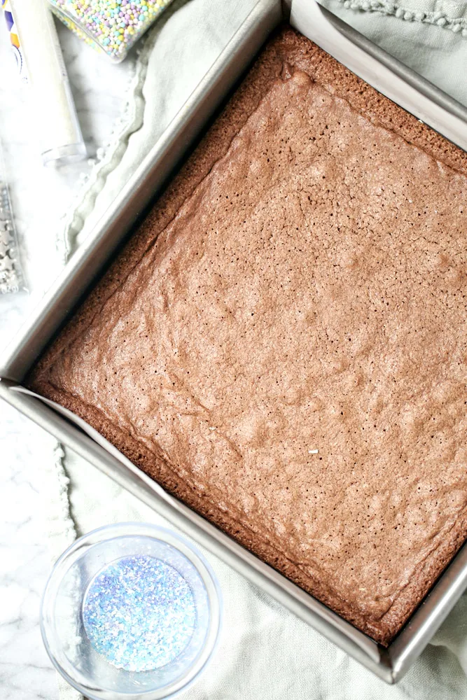 Homemade brownies unfrosted with sprinkles on the side.