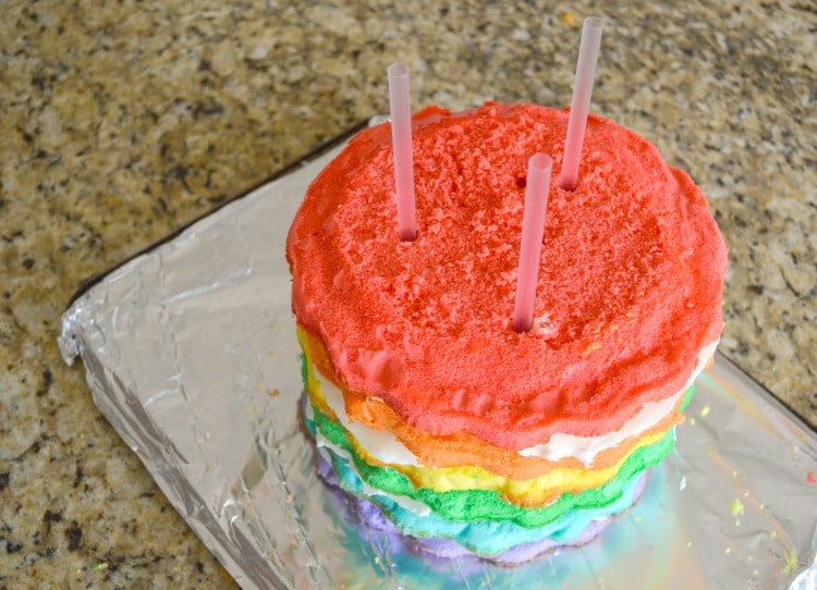 How to make a rainbow layer cake. Shows rainbow layers with straws as inner supports of cake.