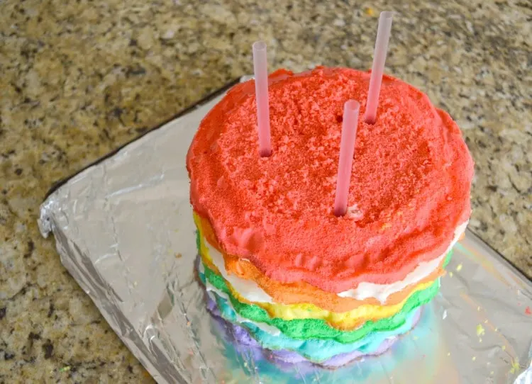 How to make a rainbow layer cake. Shows rainbow layers with straws as inner supports of cake.