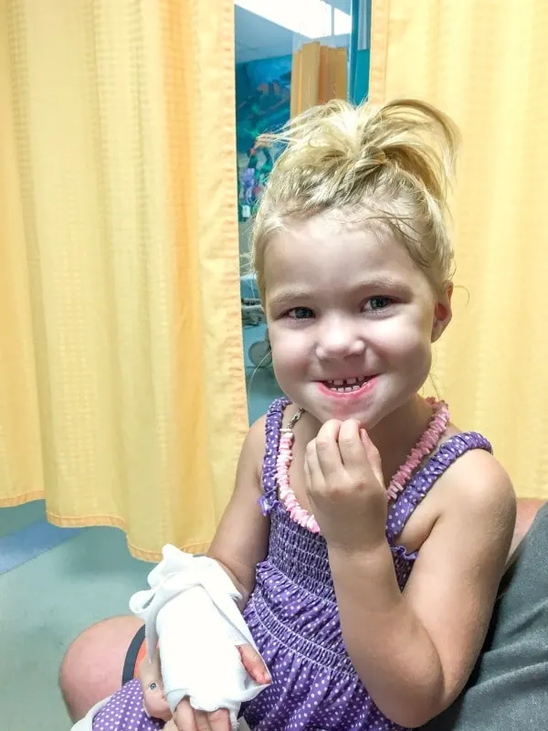 Little girl in emergency room with bandage on hand from cuts.