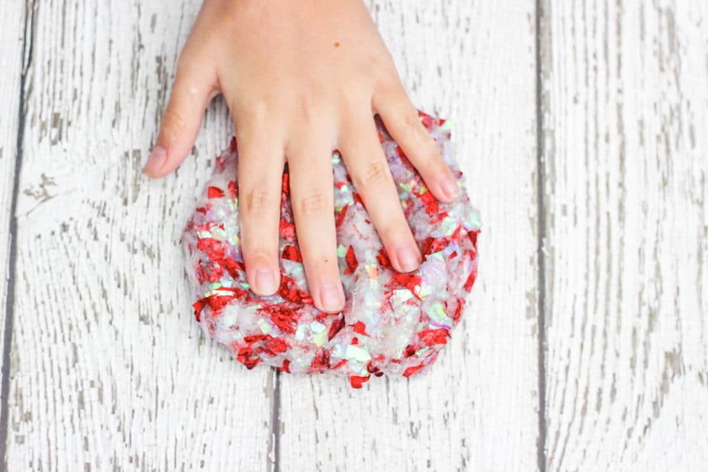 Girls hand on top of homemade slime with confetti