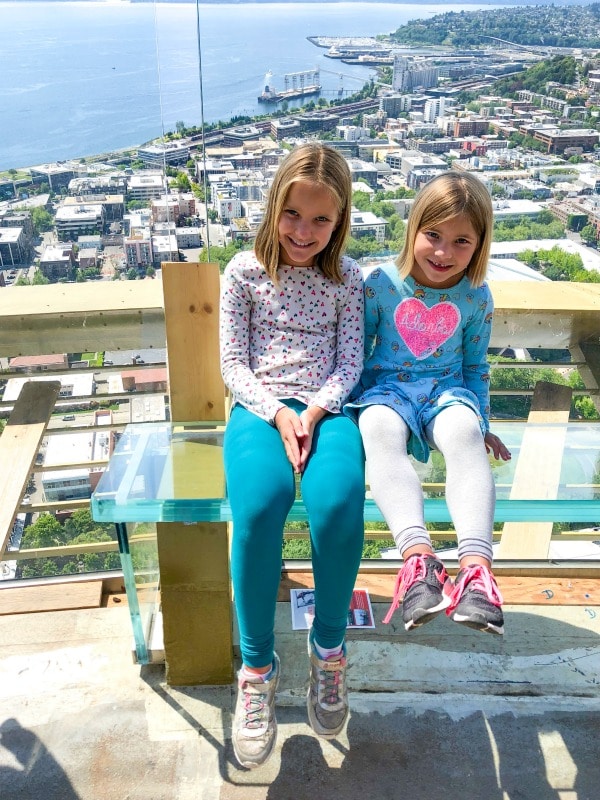 Girls sitting on glass bench at the top of the Space Needle in Seattle, Washington.