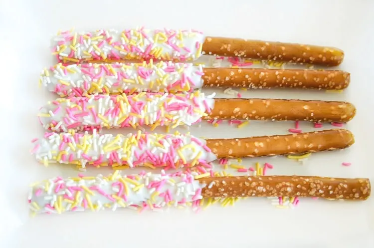White chocolate dipped pretzel rod with sprinkles at room temperature