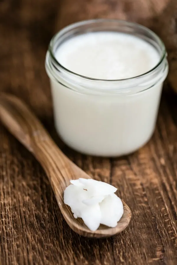 Coconut oil uses for with coconut in spoon to use on hair, skin, and nails
