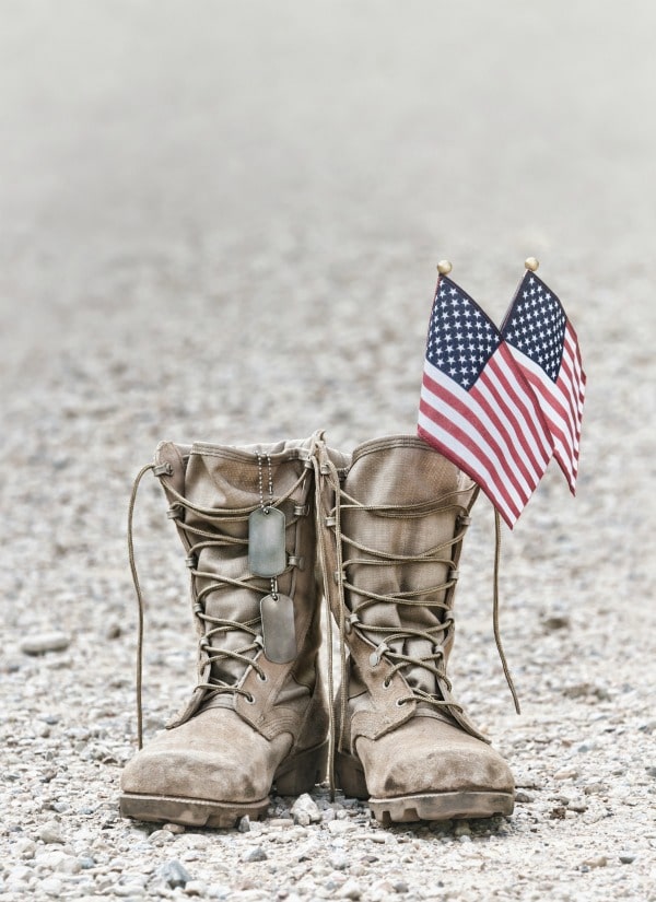 Military boots with American flags and dog tags on ground for Memorial Day