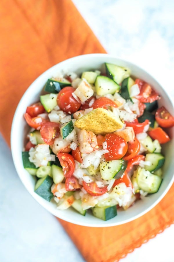 Avocado shrimp cucumber and tomato salad in bowl.