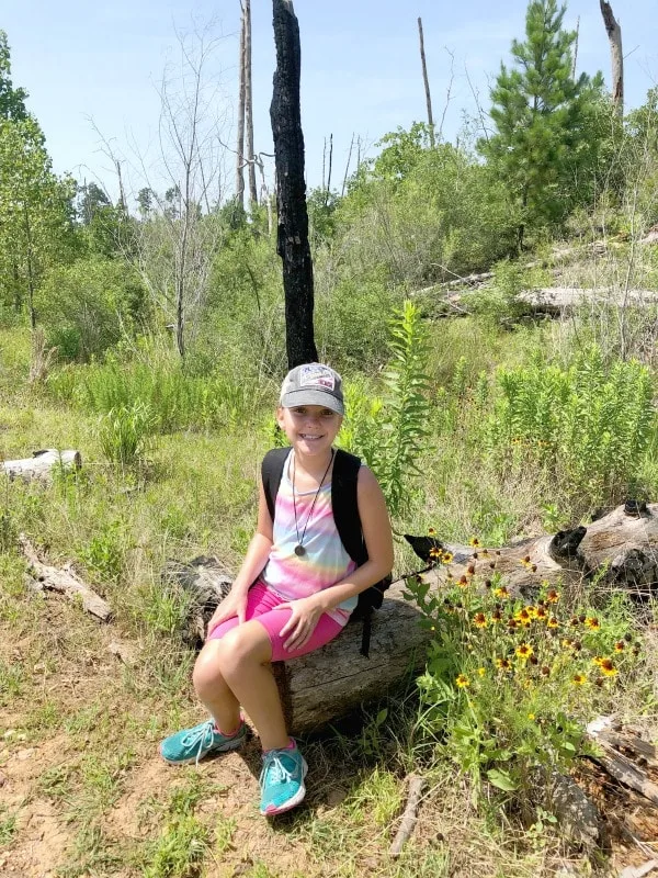 Girl sitting on burned pine log in Bastrop State Park