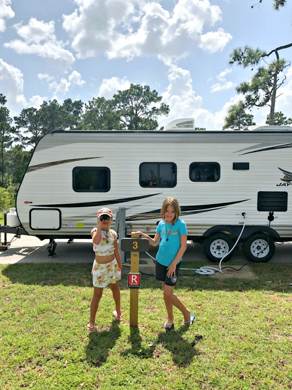 Travel trailer with girls posing in front of it at Bastrop State Park