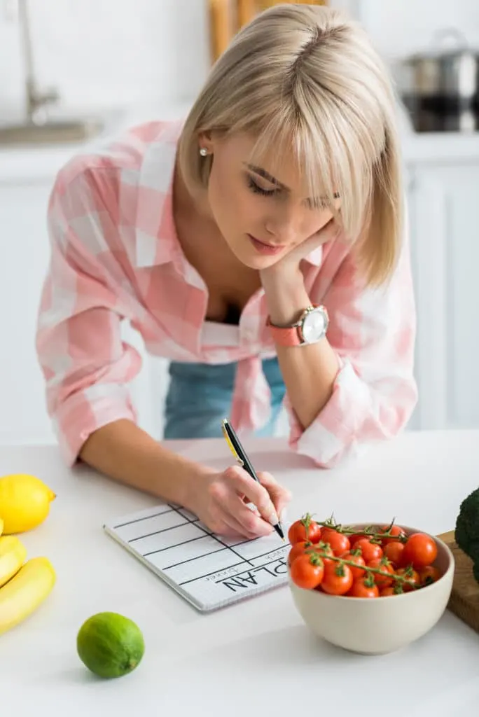 Woman meal planning with grocery list in kitchen