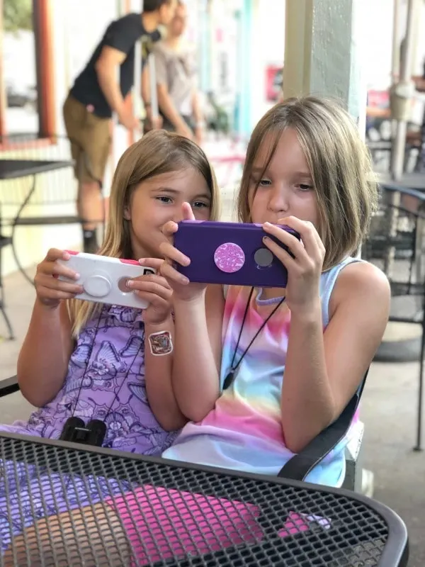 Girls sitting together playing educational apps on cell phones.