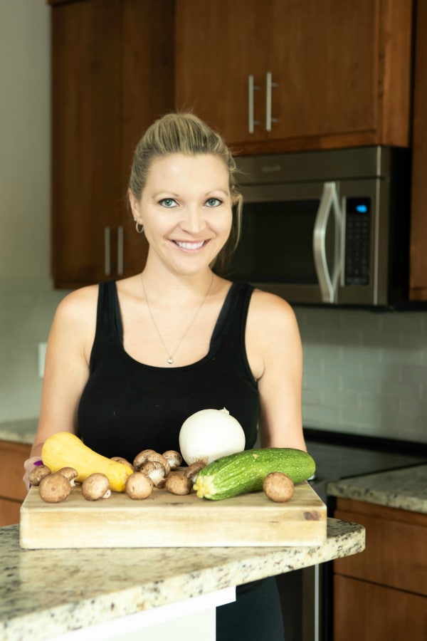 woman standing in front of fresh vegetables