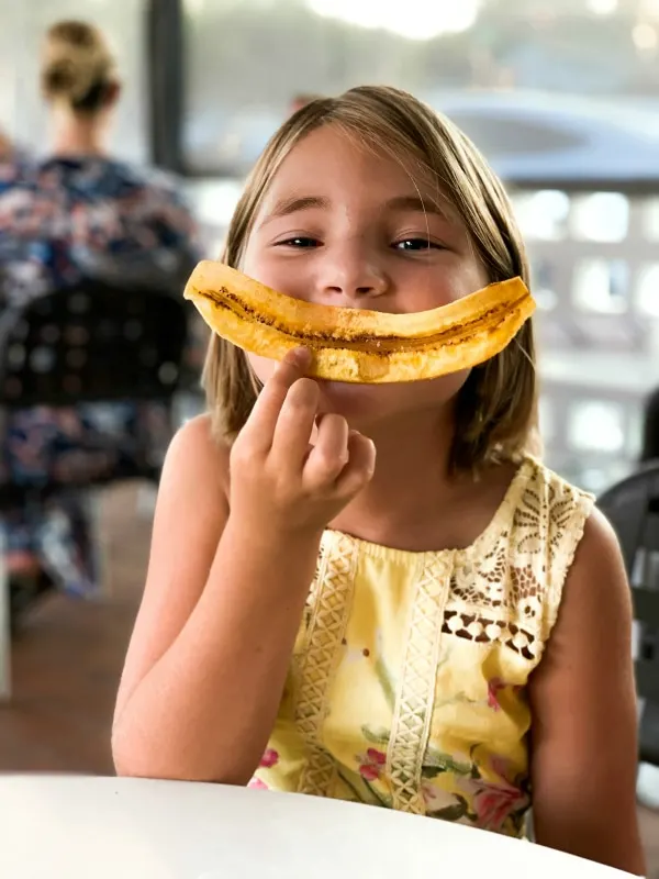 girl posing with plantain smile at restaurant