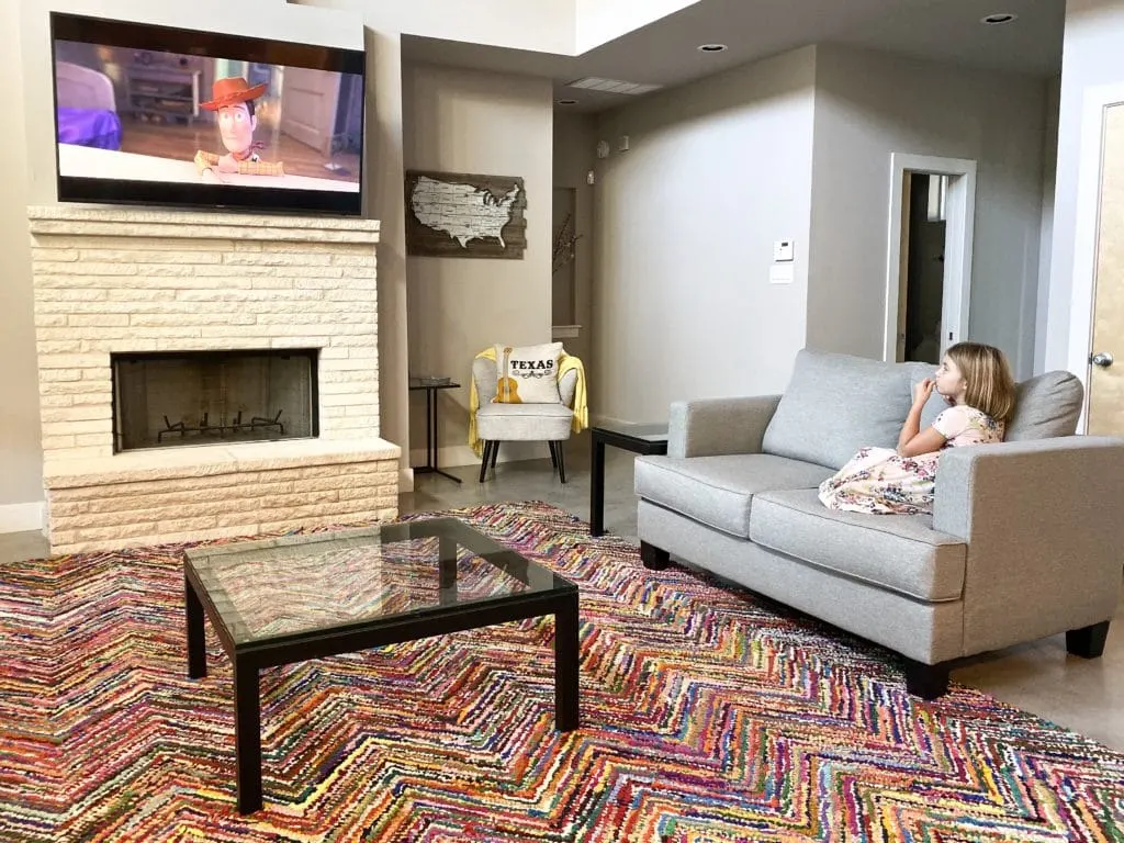 Young girl watching Toy Story 4 on TV with colorful rug