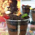 Lion King recipe of Dirt Cups with Gummy Worms on table closeup.