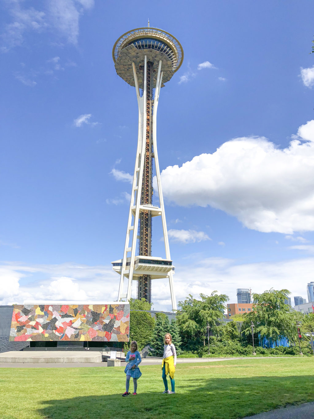 Girls standing in green space underneath the Seattle Space Needle