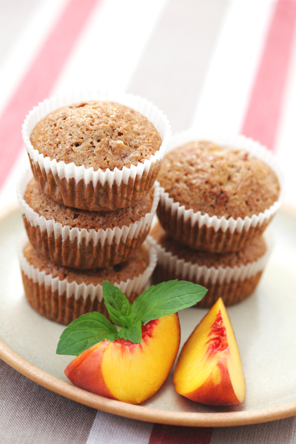 Moist peach muffins on plate with peaches