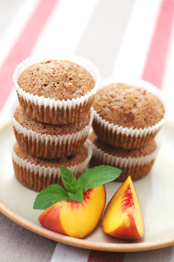 Moist peach muffins on plate with peaches
