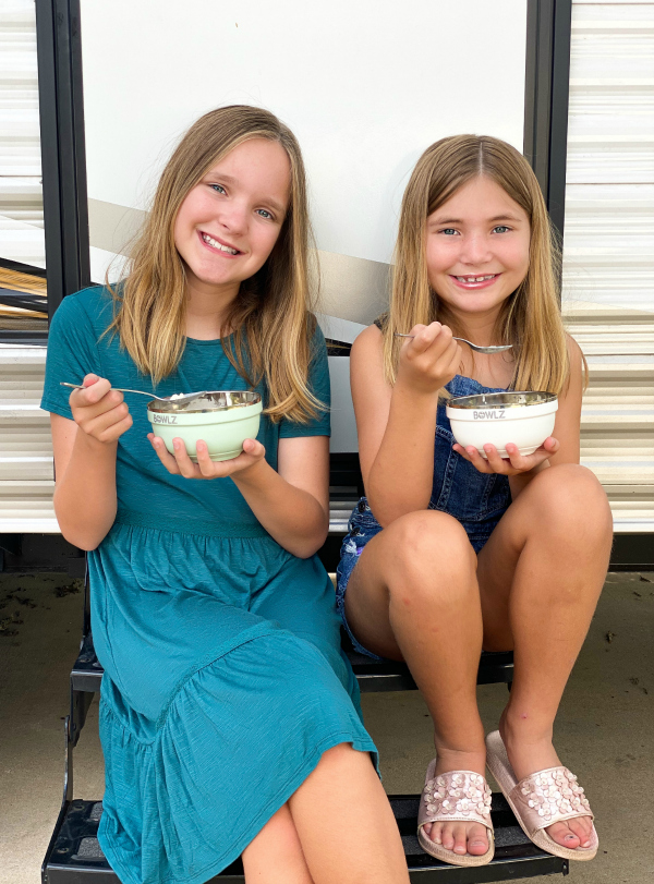 girls eating ice cream outside of travel trailer while camping