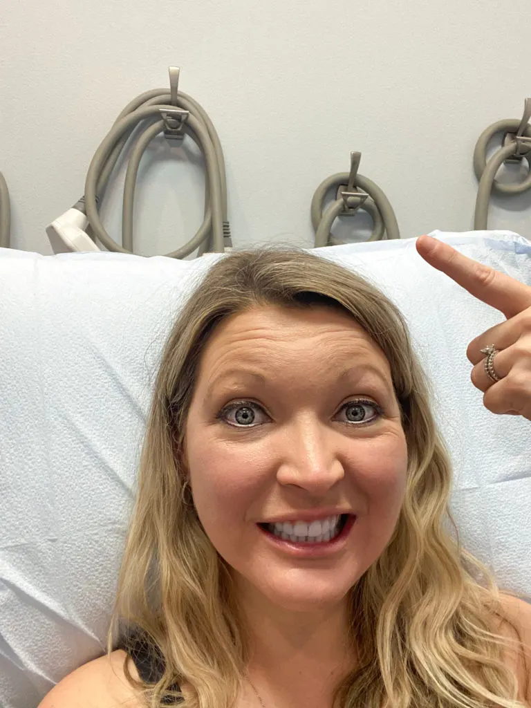 Woman getting Coolsculpting and pointing to fat freezing treatment hoses on wall behind