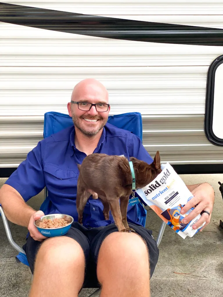 man holding dog eating with food in dog food bag
